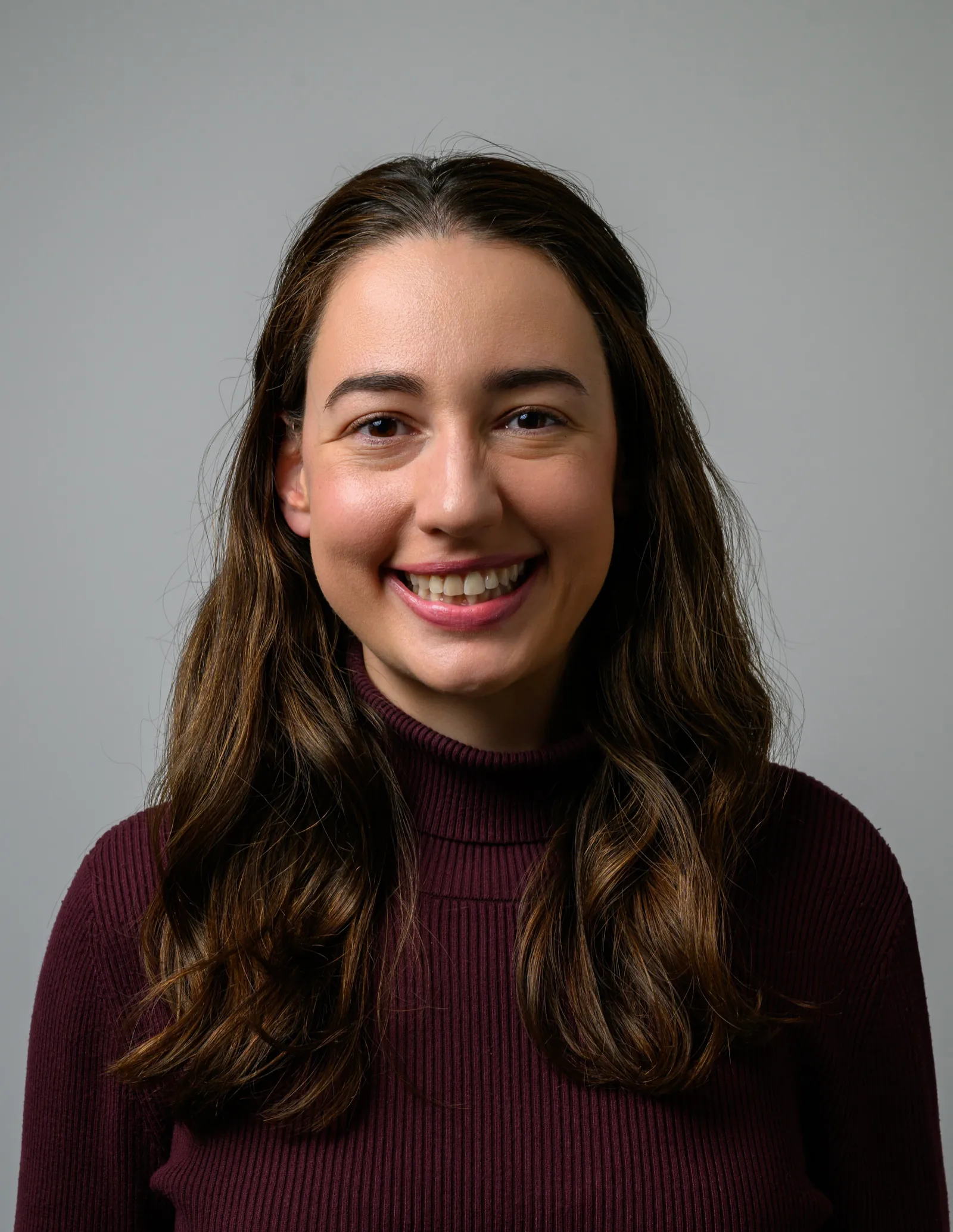 Professional headshot examples: woman smiling in a tight crop on a plain gray backdrop.