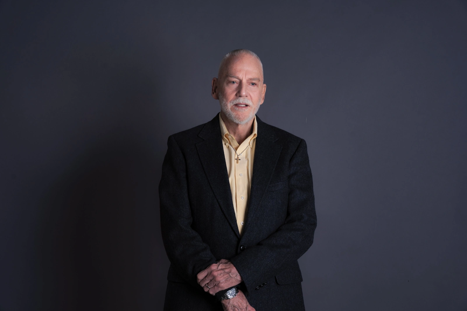 Professional headshot examples for speaker bios: man in a blazer on a dark charcoal backdrop.