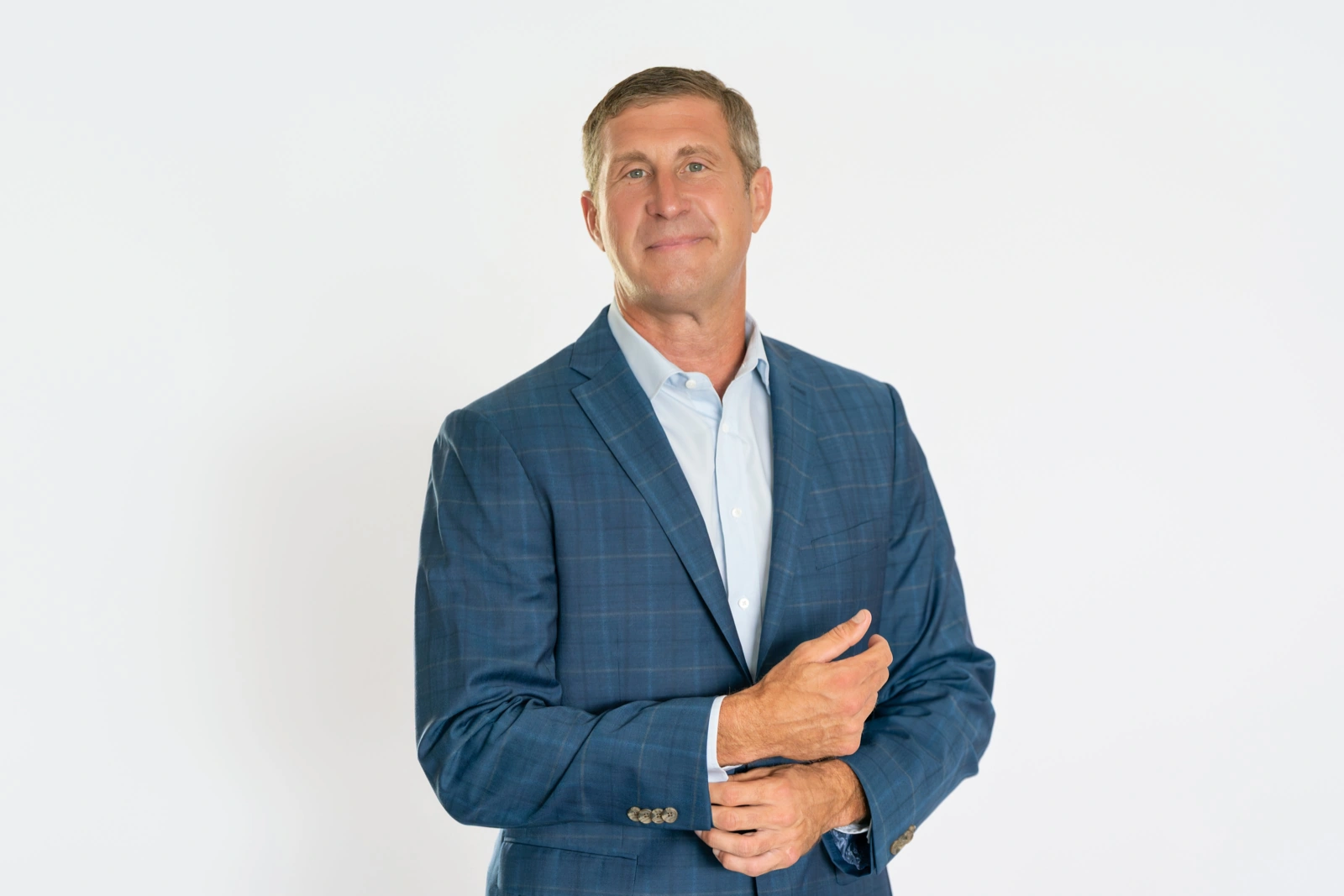 Male poses for hands: man in a blue blazer adjusting his shirt cuff and smiling
