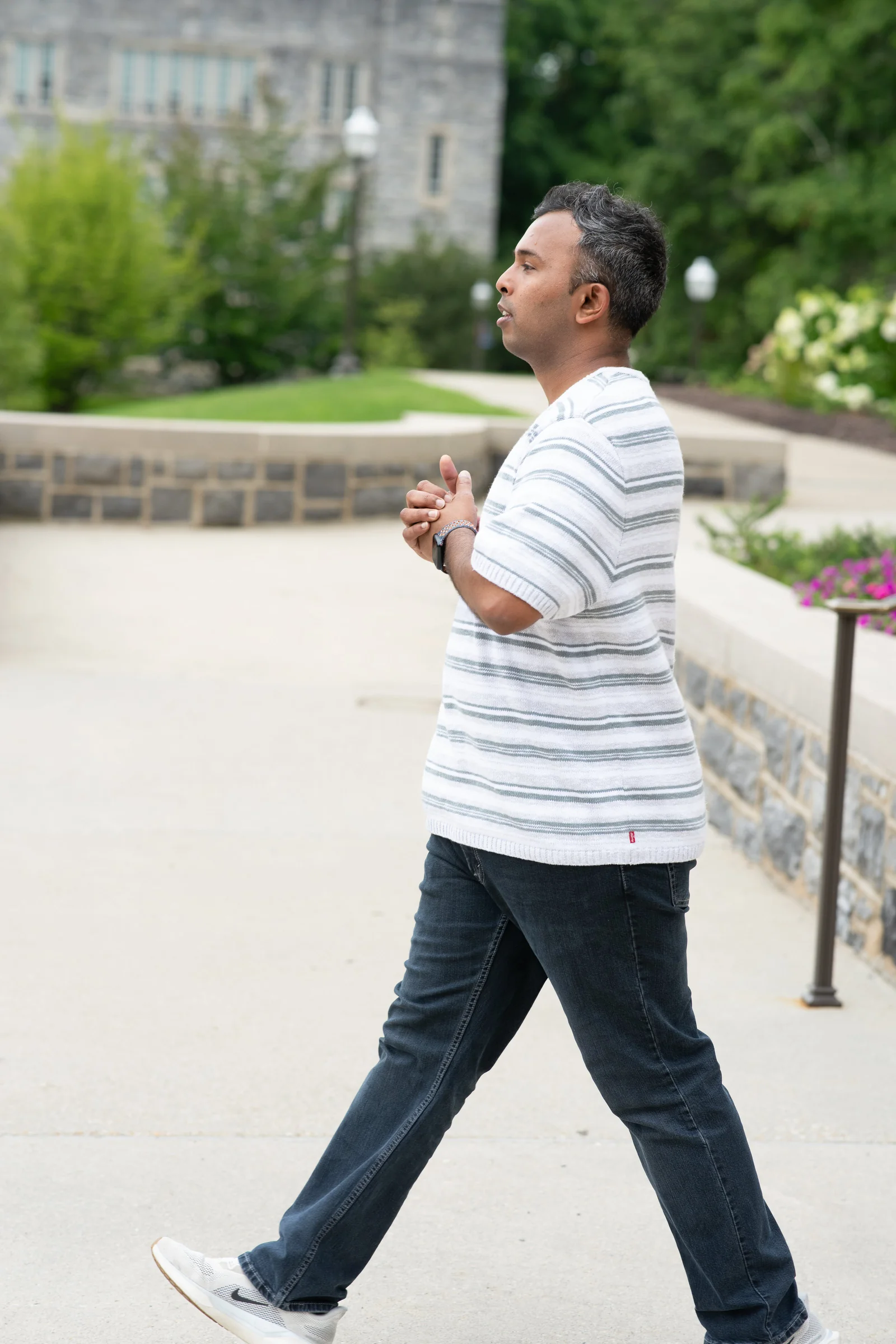 Walking male poses: man mid-stride on a sidewalk in a striped tee and jeans
