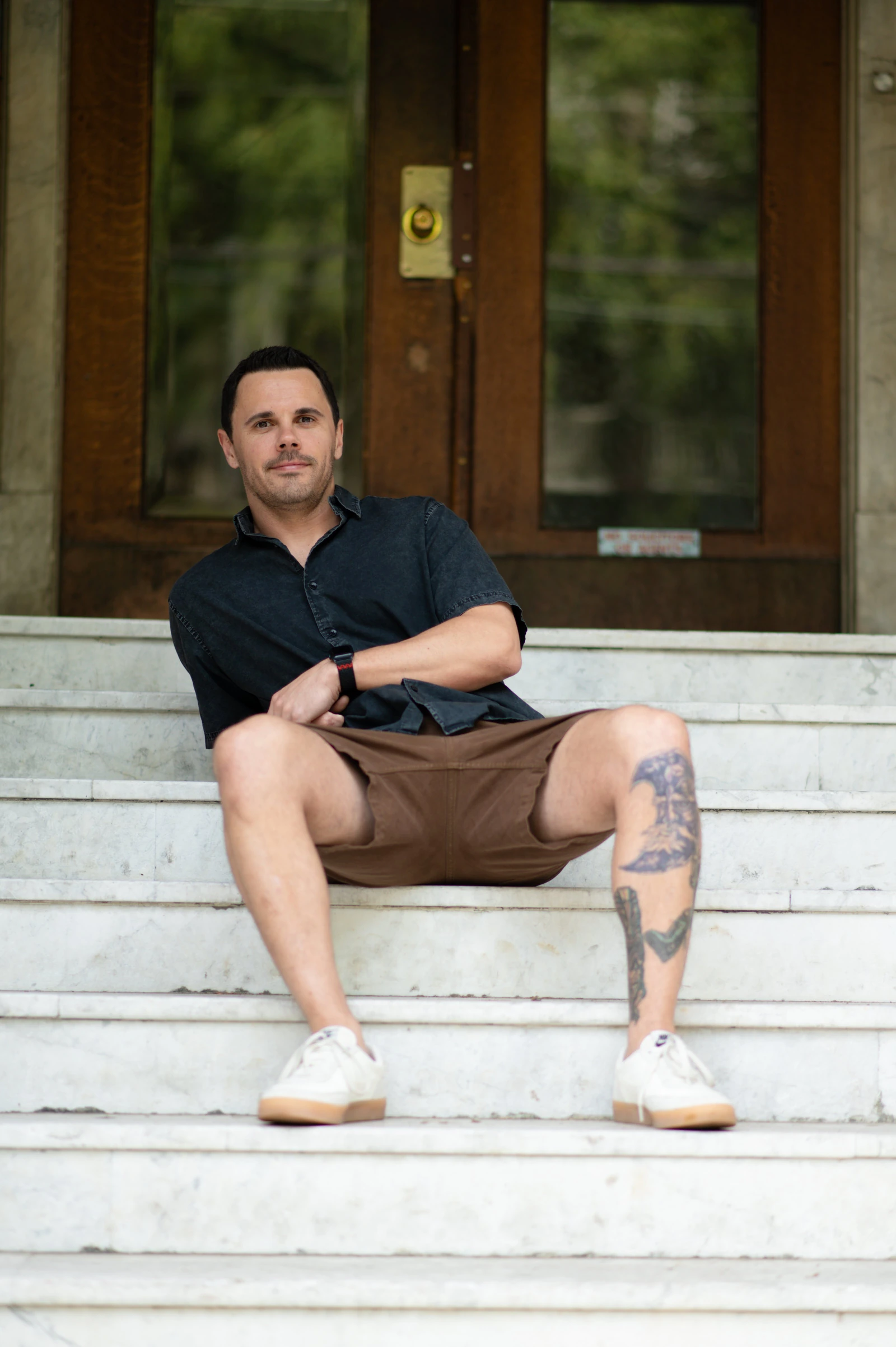 Seated male poses: man sitting on white stone steps, forearm resting on his knee