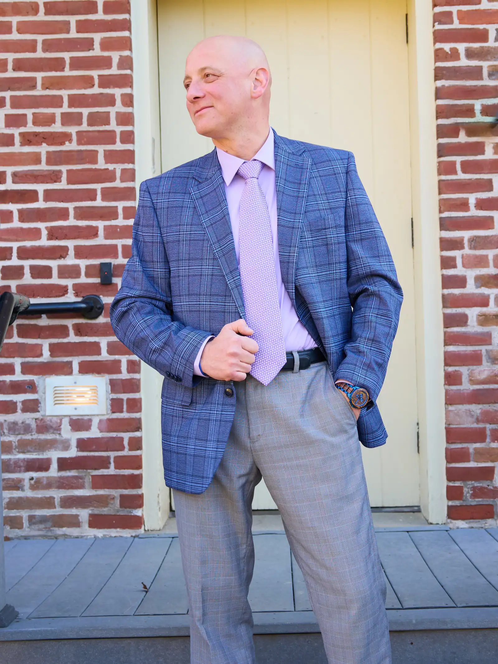 Standing male poses: man in a plaid blazer, hand in pocket, looking away by a door