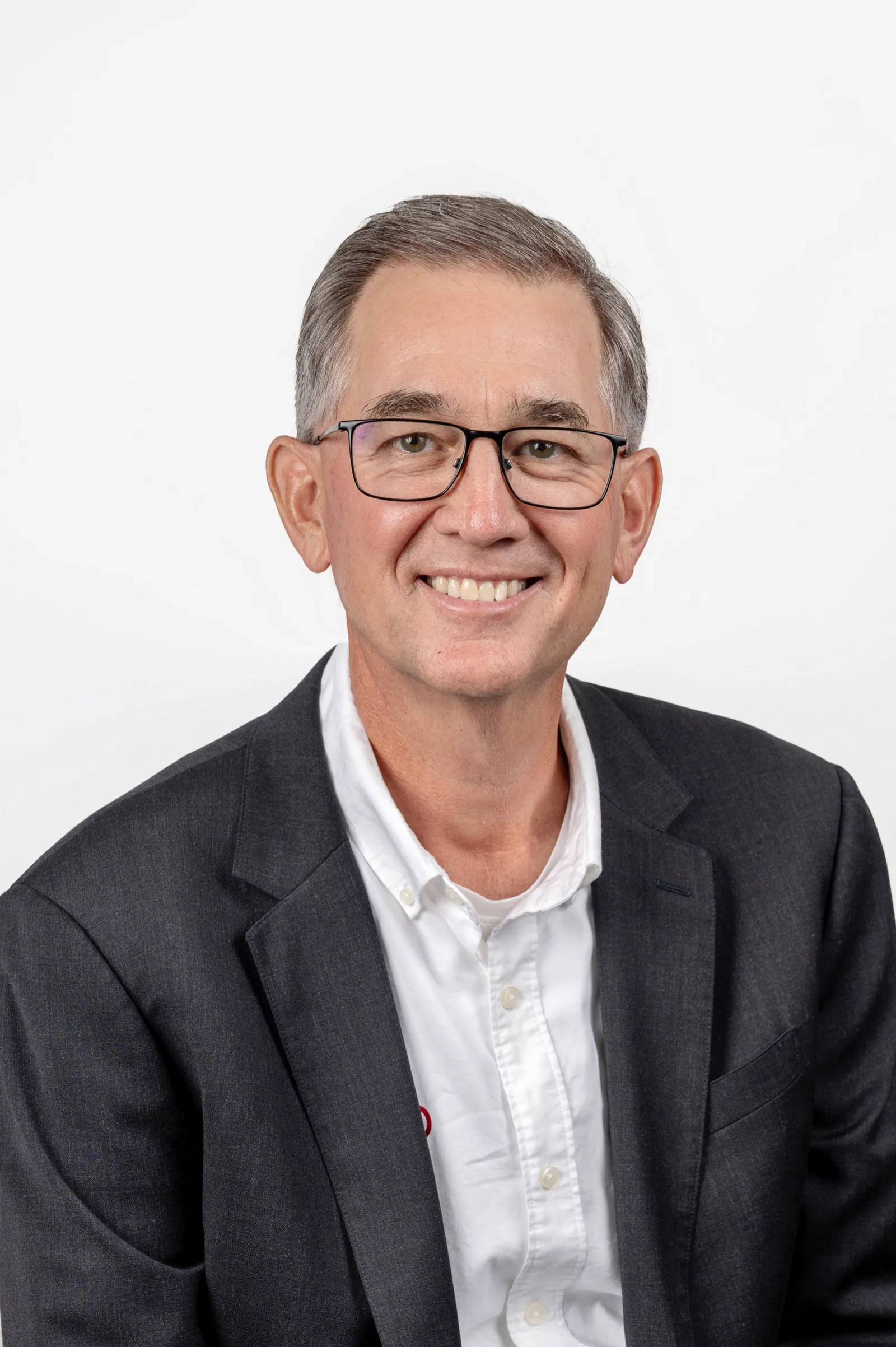 Male poses for headshots: man in glasses and a blazer with a slight turn and smile
