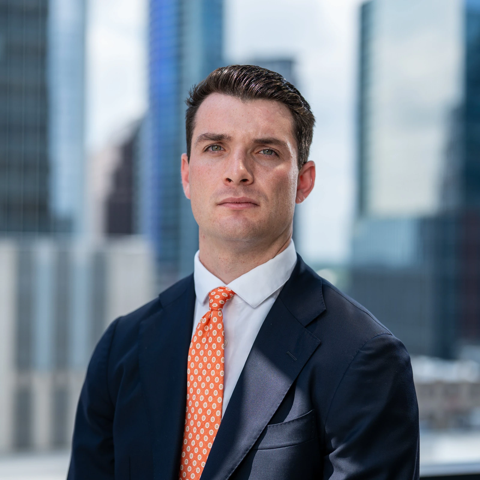 Male poses up close: man in a suit and orange tie with chin forward and jaw defined
