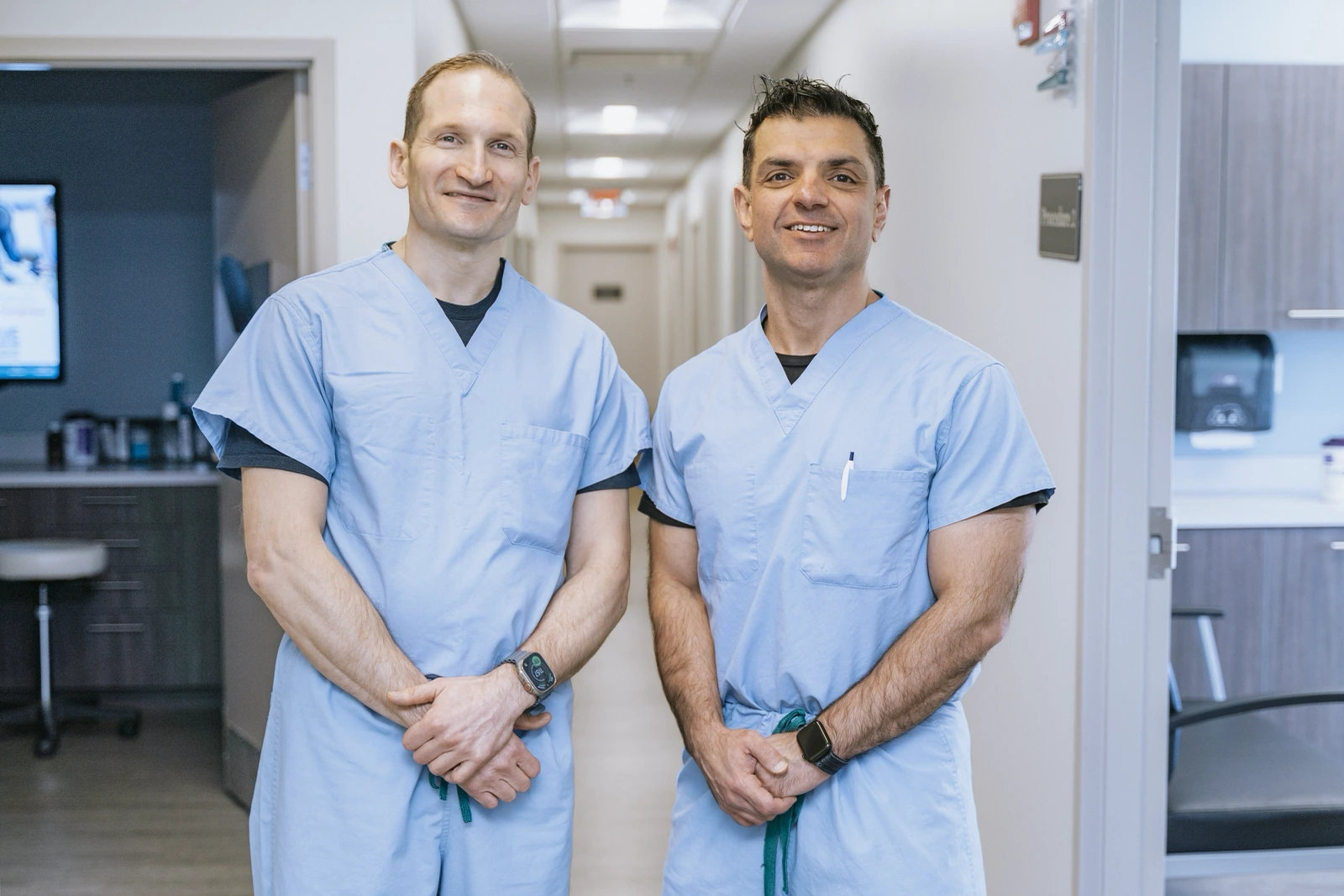 On-site doctor headshots: two providers in scrubs smiling in a clinic hallway
