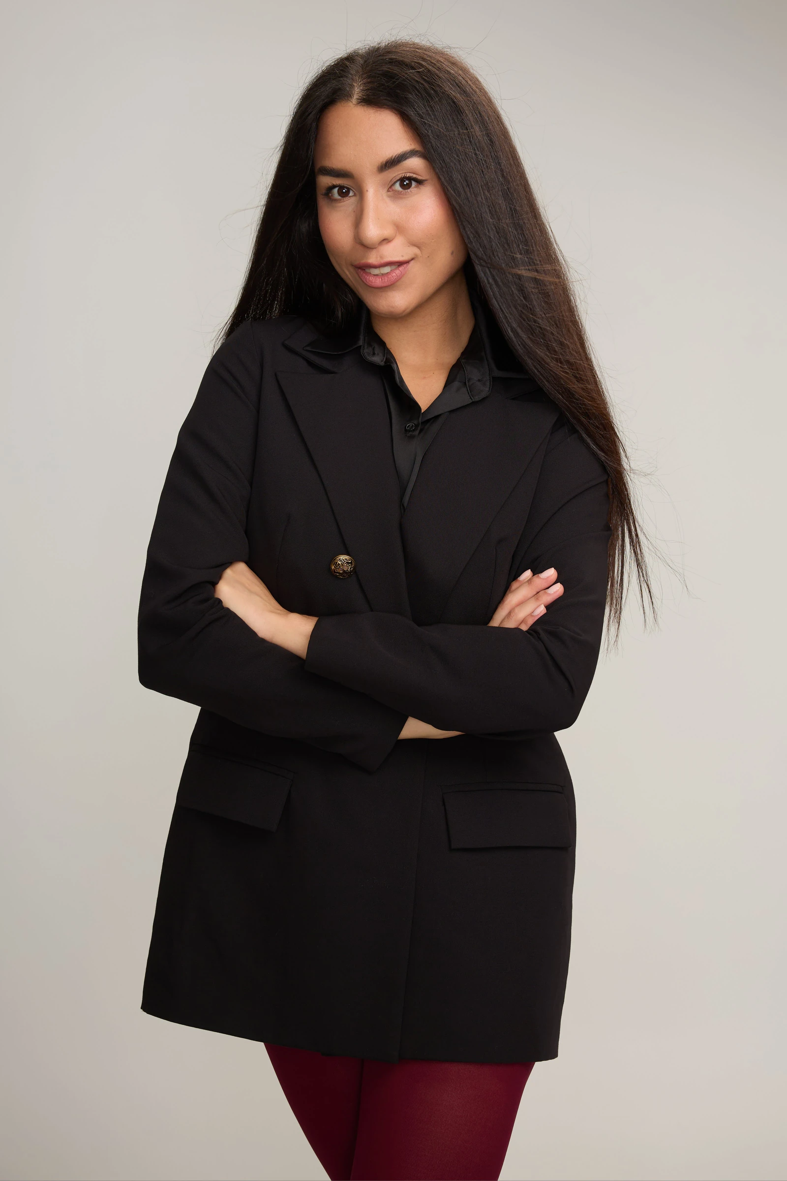 Poses for women: arms loosely crossed in a black blazer against a plain wall