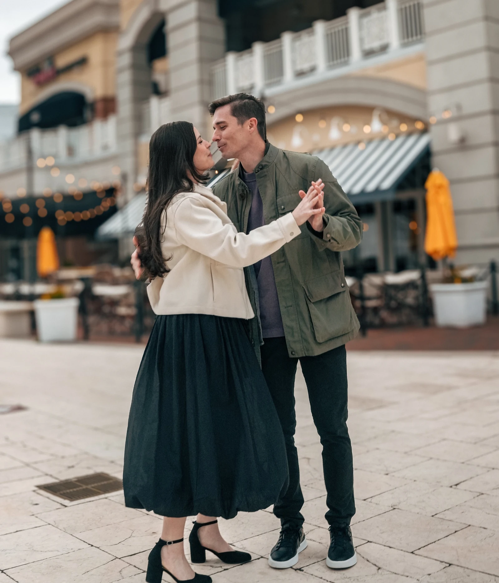 Couple poses in a city plaza: a slow dance that stops just before a kiss