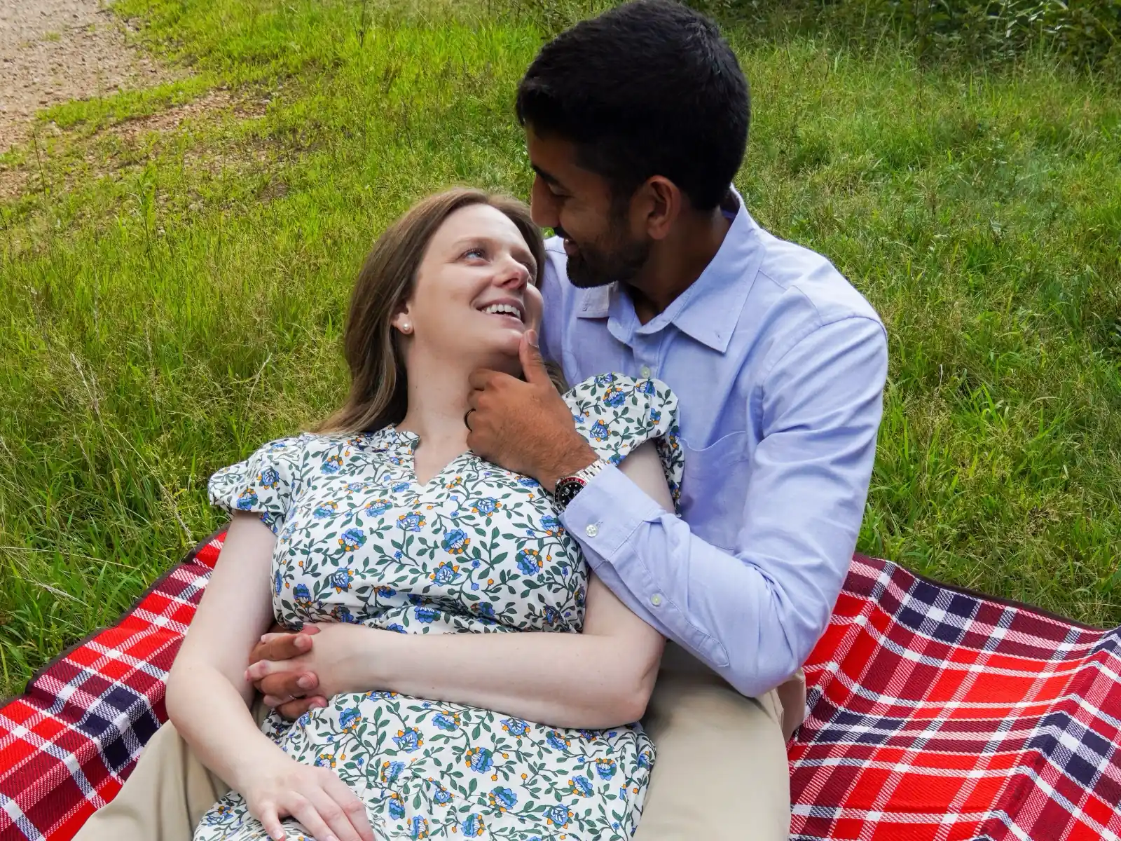 Nestled couple poses: leaning back into a partner on a tartan picnic blanket
