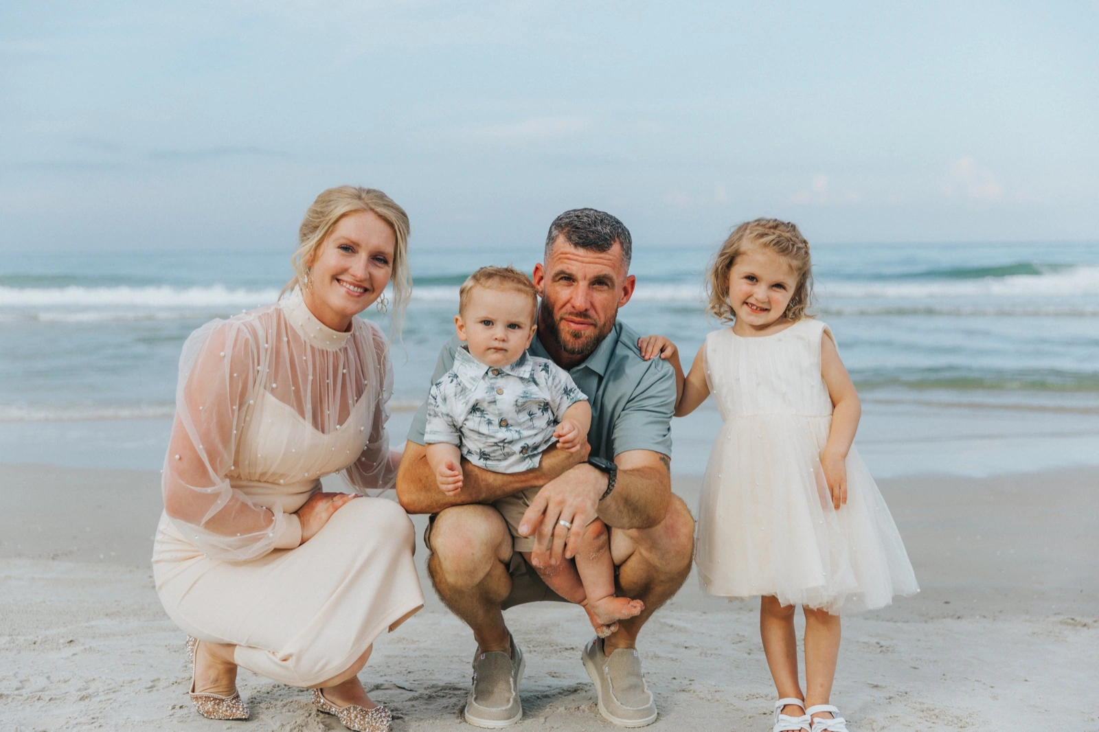 Anniversary photo ideas with kids: a couple on the beach with their toddler and daughter