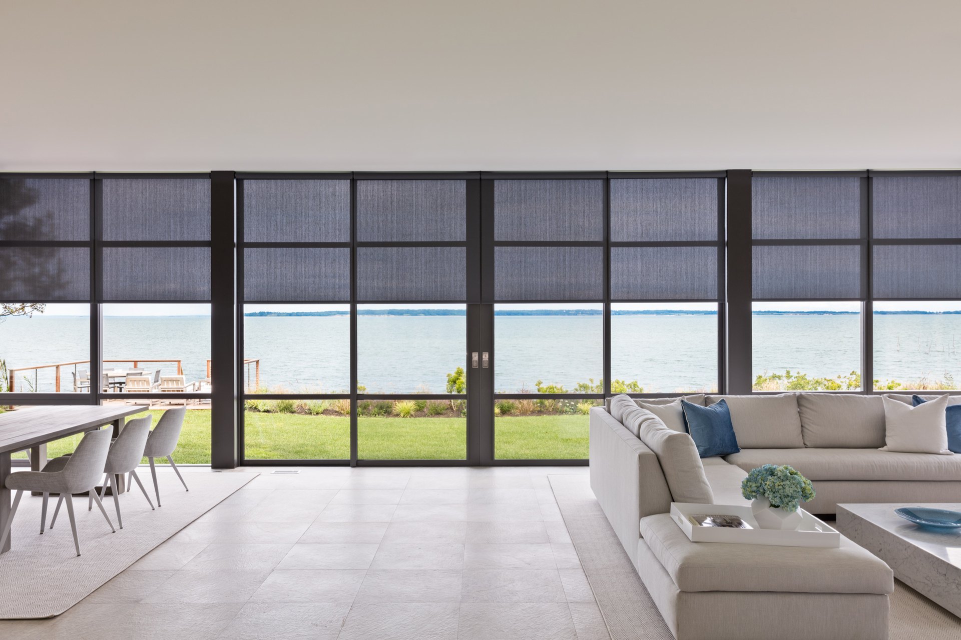 Luxury interior with automated shades and drapery overlooking a coastal view