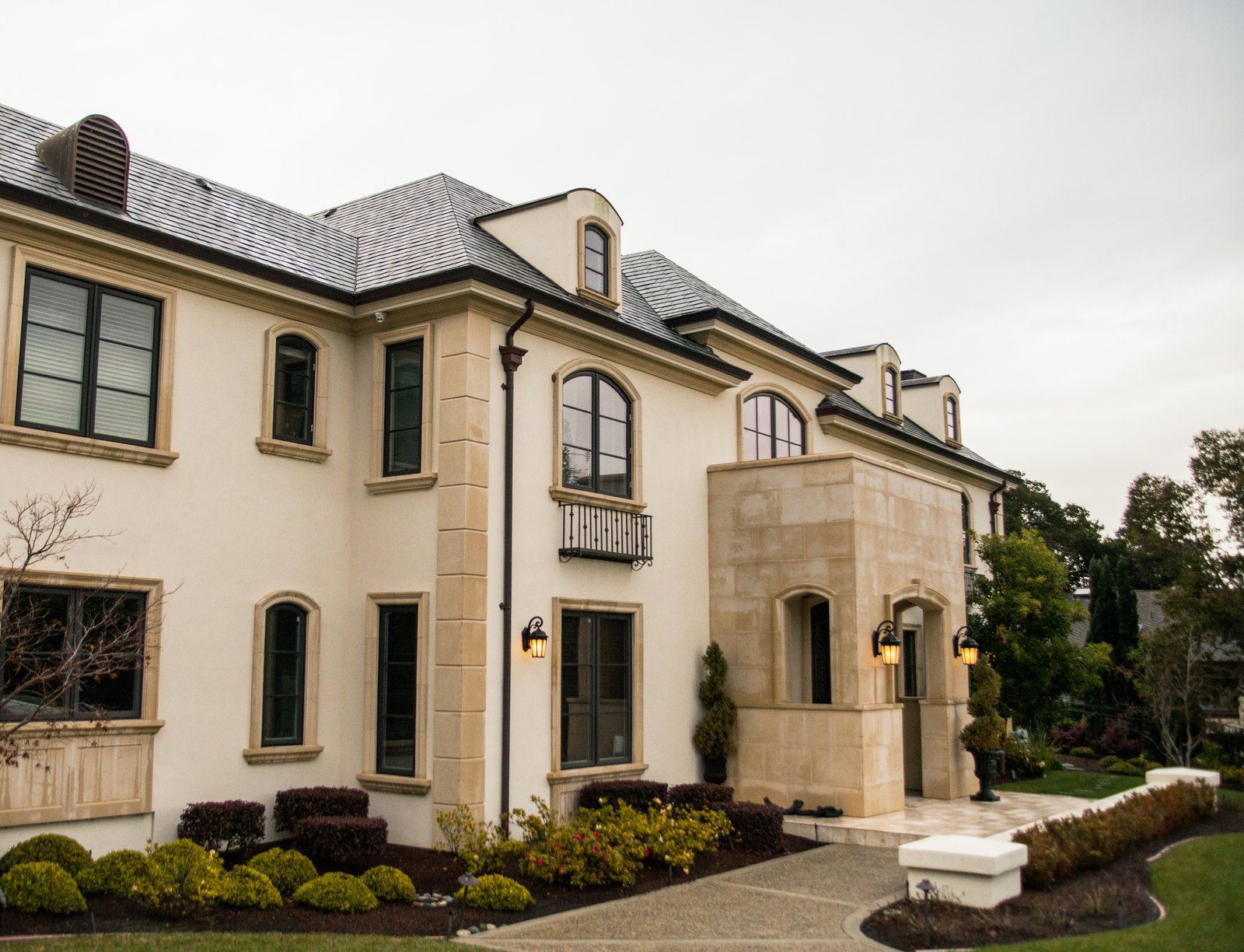 French chateau style estate exterior with limestone trim and lit entry lanterns