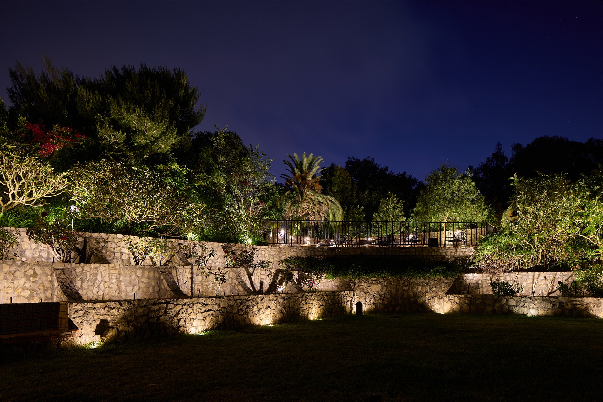Architectural landscape lighting washing terraced stone walls at night