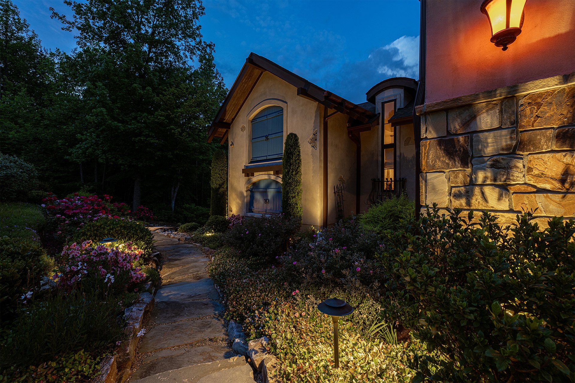 Luxury residence and landscaped garden path illuminated at dusk