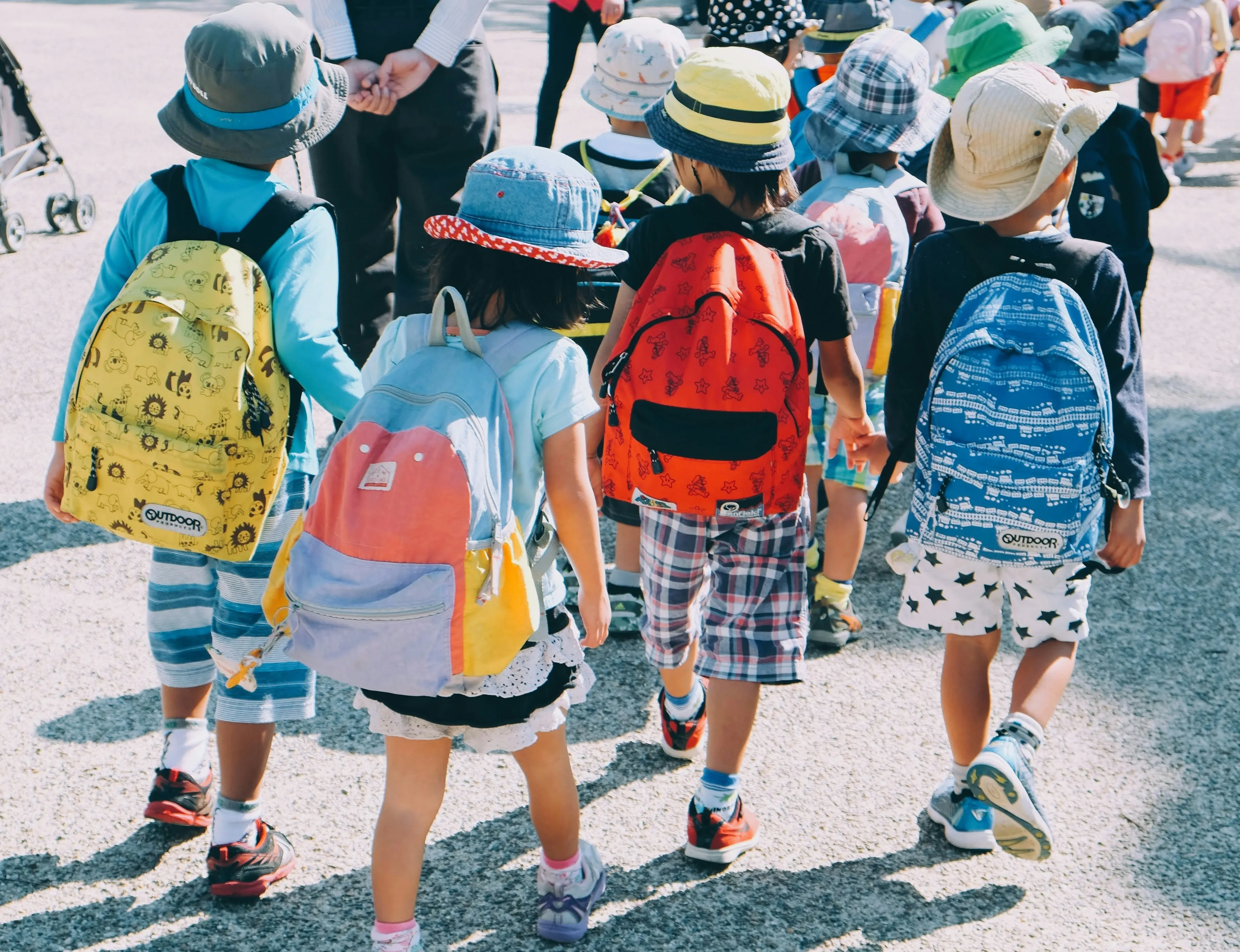 Four children with backpacks walking into school