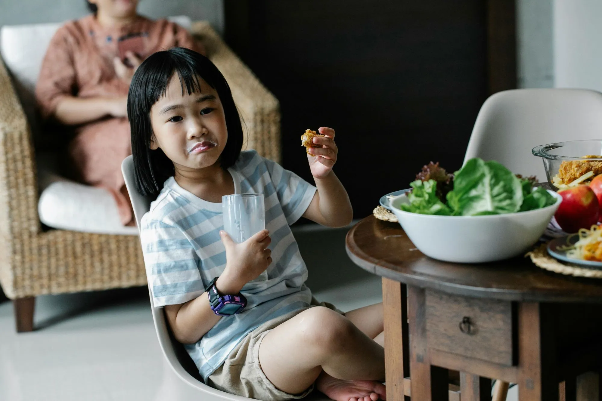 Young child sitting unhappily at a dinner table