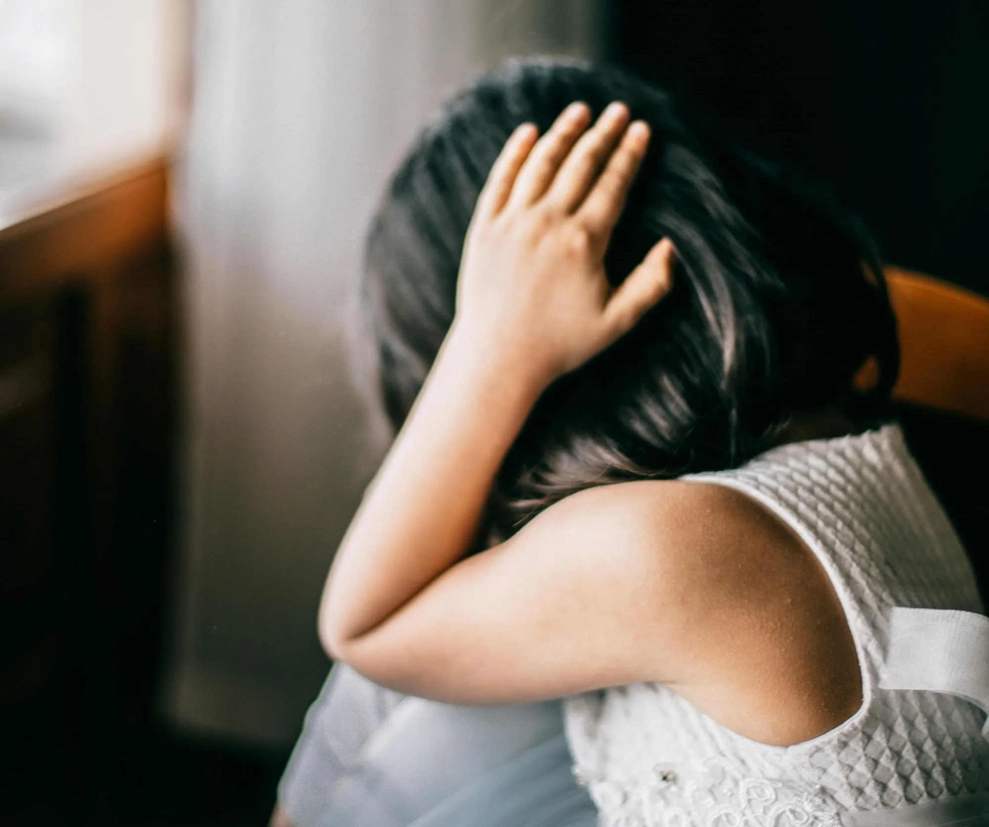 A child turned away with their head in their hands