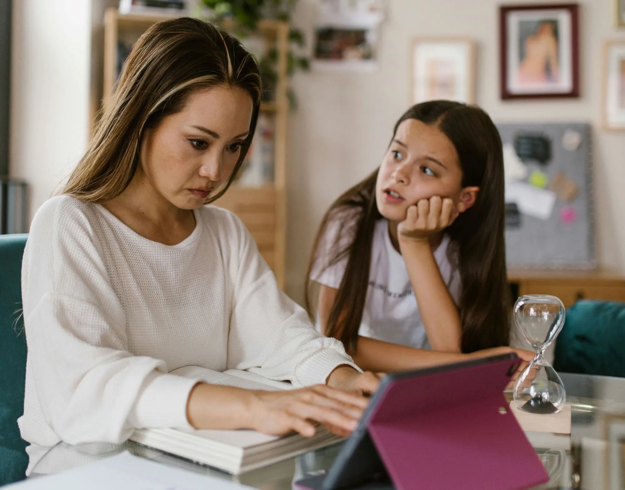 A child is distracting her mother who is trying to work on her laptop