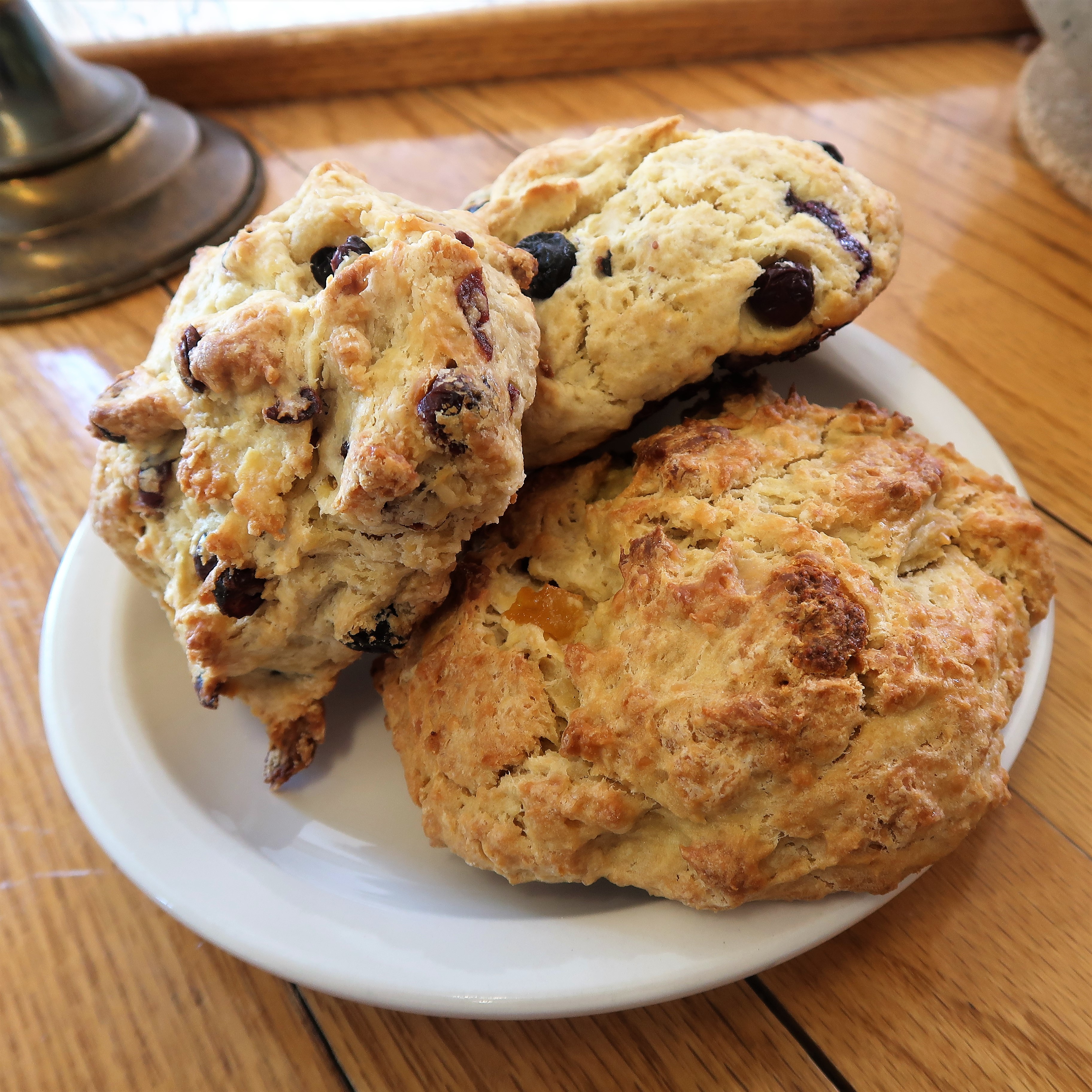 Three different kinds of scones are stacked up on a plate: one with cranberry, one with blueberry, and one with peach