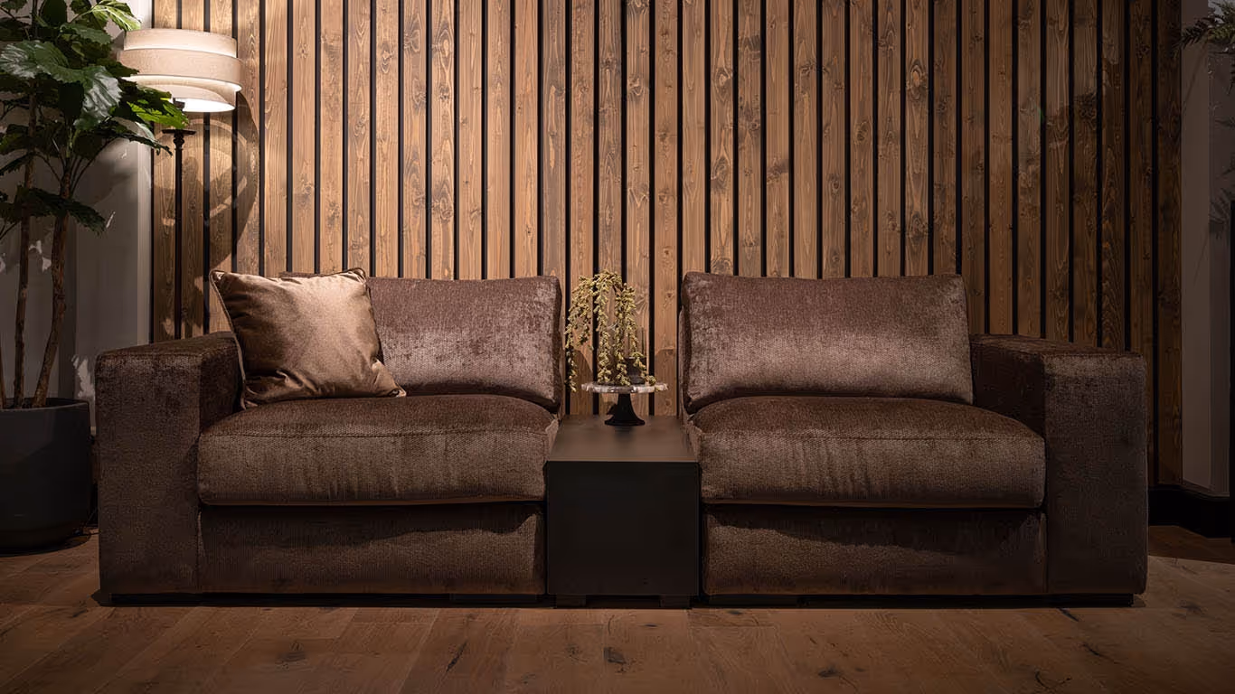 UrbanSofa Carl-bank in warme bruine tinten met houten lamellen achtergrond