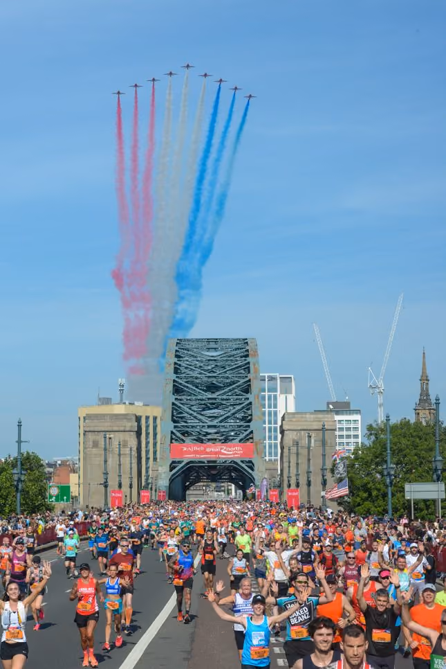 Great North Run screne with runners coming across a bridge and a fly past of aircraft