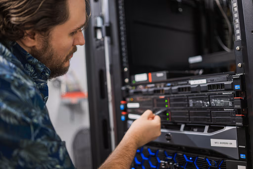 Man with beard interacting with server hardware inside a data center rack.