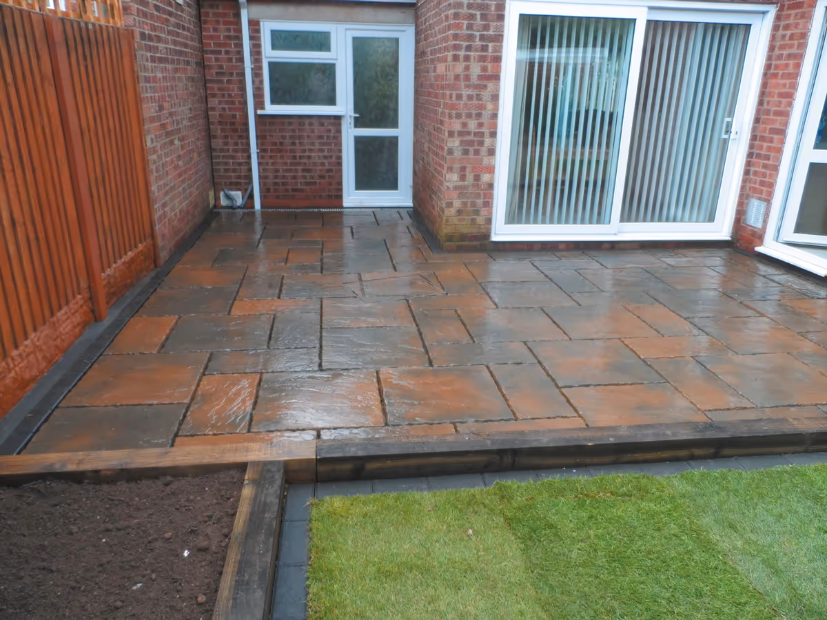 Two size autumn gold concrete patio with matching circle, patio edged with standard charcoal blocks, retaining sleeper beds and new lawn - angle 4