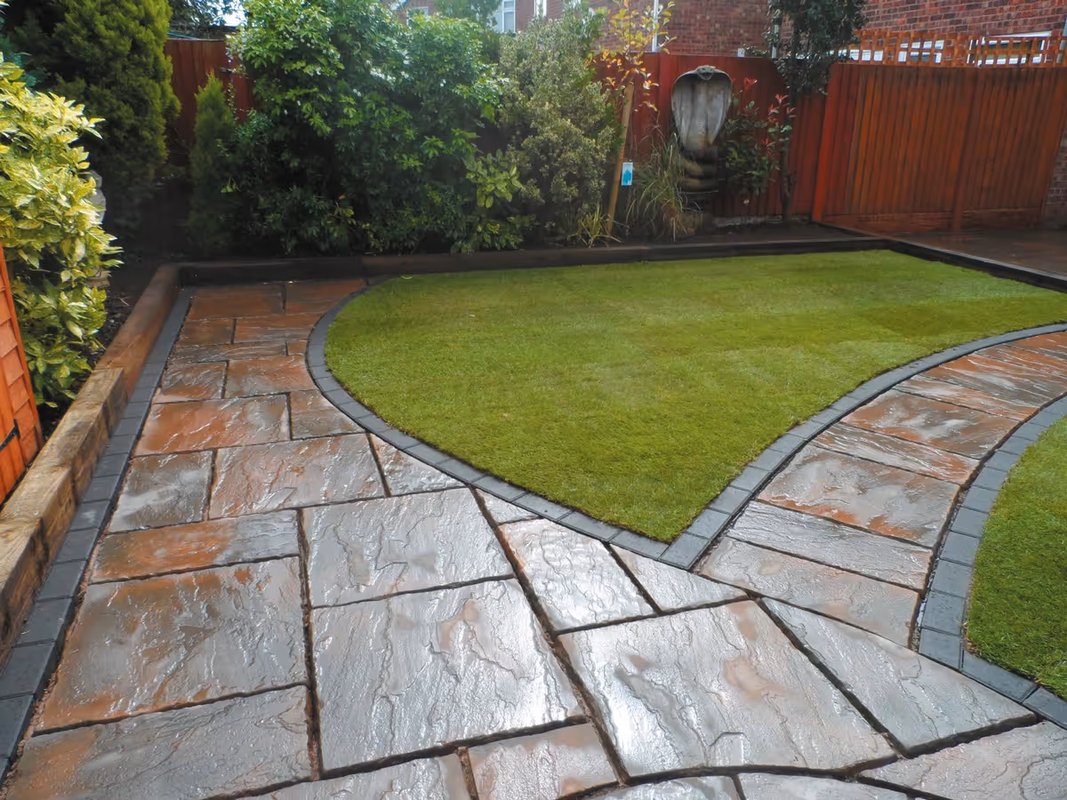 Two size autumn gold concrete patio with matching circle, patio edged with standard charcoal blocks, retaining sleeper beds and new lawn - angle 2