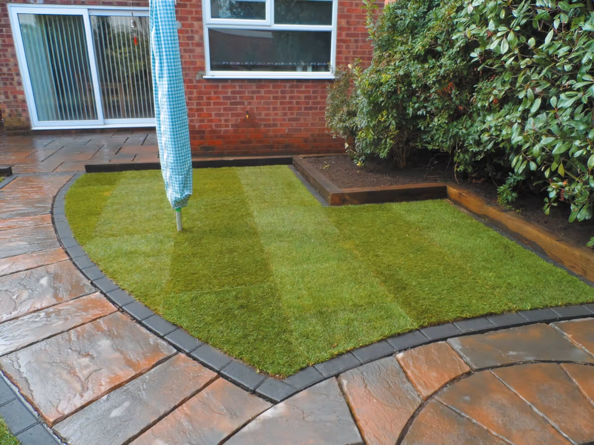 Two size autumn gold concrete patio with matching circle, patio edged with standard charcoal blocks, retaining sleeper beds and new lawn - angle 3