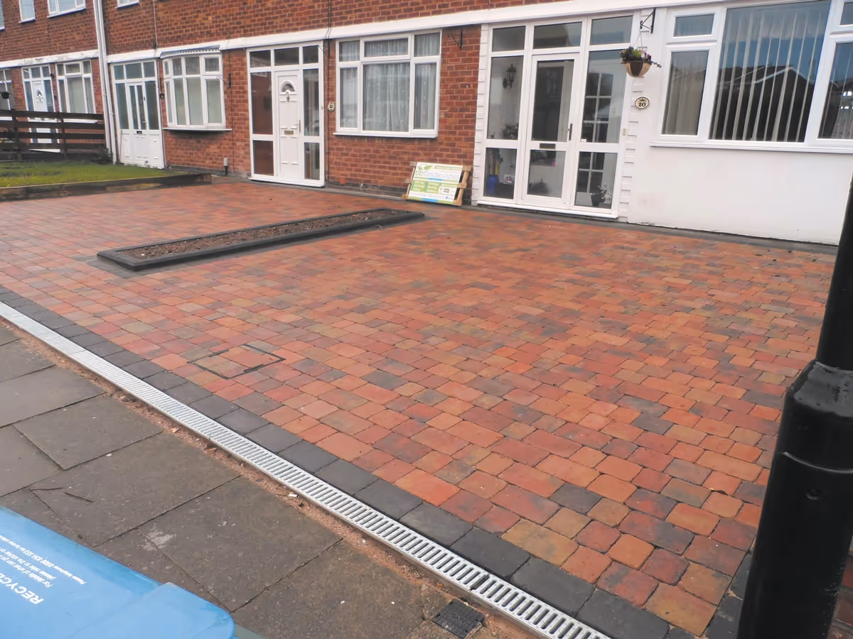 Orchid flame Rumbled paving set driveway with single charcoal border, planter, ACO drainage and boundary wall installed