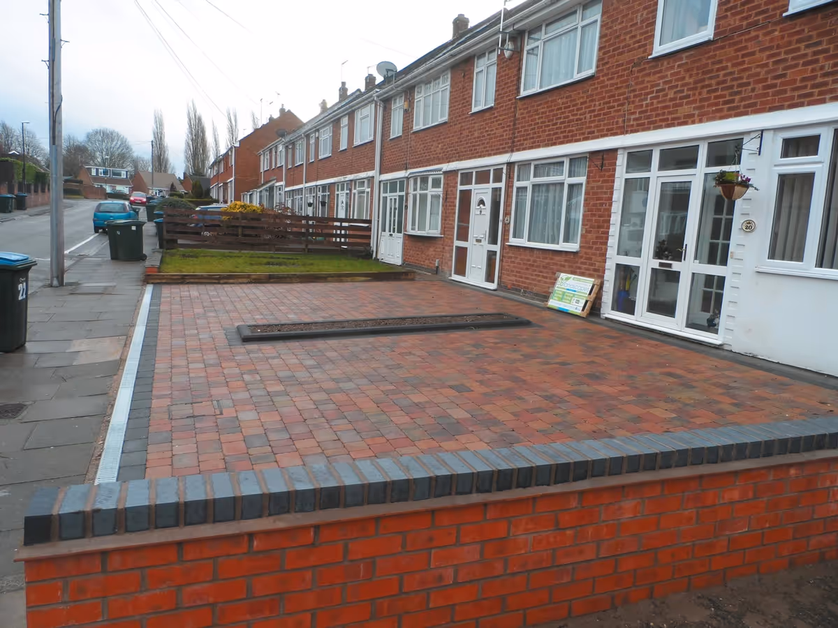 Orchid flame Rumbled paving set driveway with single charcoal border, planter, ACO drainage and boundary wall installed - angle 3