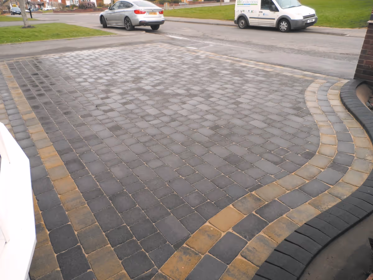 Charcoal Rumbled paving set driveway with a triple border using burnt willow, inset manhole tray, K.L kerb set planter and an ACO channel drainage system.