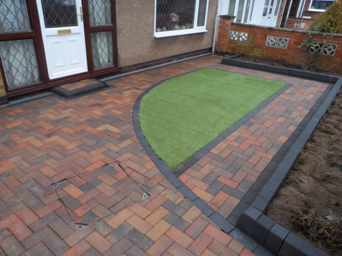 Autumn mix paving driveway with charcoal border, K.L kerb set planters, inset manhole tray, ACO drainage, K.S kerb step and artificial lawn - angle 3