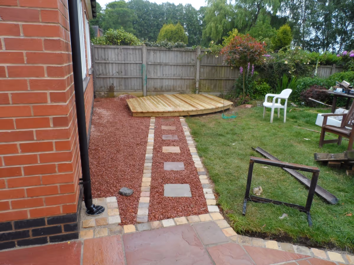 Modak natural stone patio with Raj natural stone sets, winter stone concrete walling and copings, gravel, stepping stones and decking - angle 1