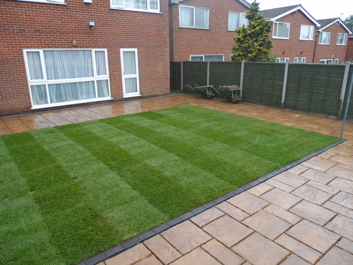 Mixed size autumn gold concrete patio with standard charcoal block border and new lawn - angle 2