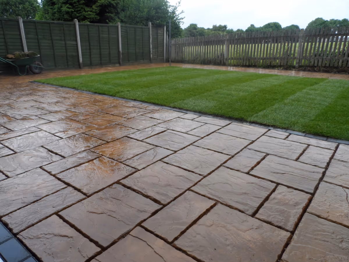 Mixed size autumn gold concrete patio with standard charcoal block border and new lawn - angle 3