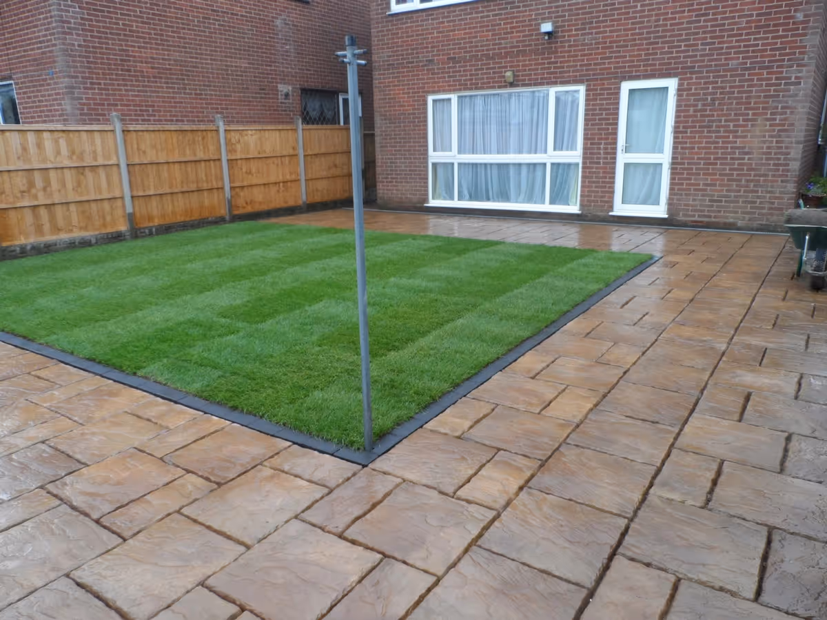 Mixed size autumn gold concrete patio with standard charcoal block border and new lawn - angle 1