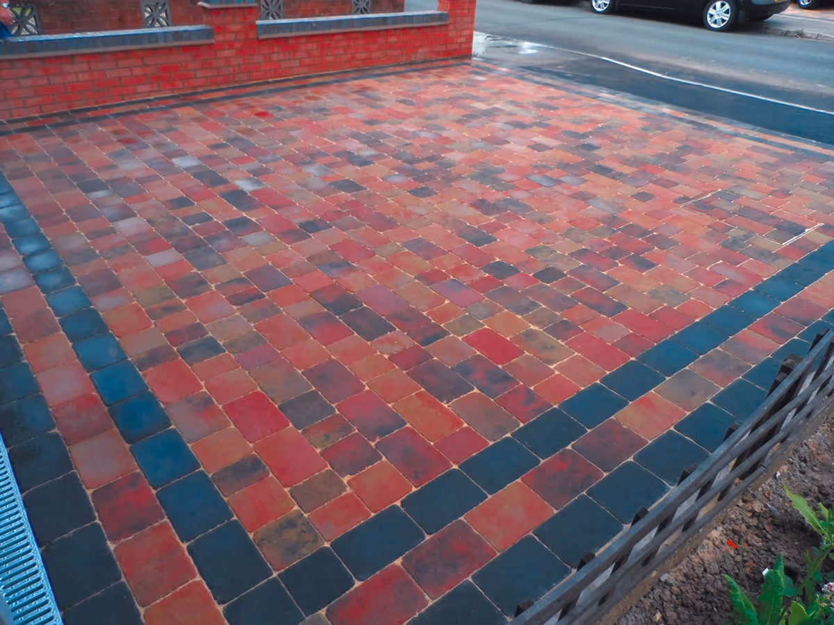 Orchid flame Rumbled paving set driveway with triple borders using charcoal, boundary wall installed and an ACO channel drainage system