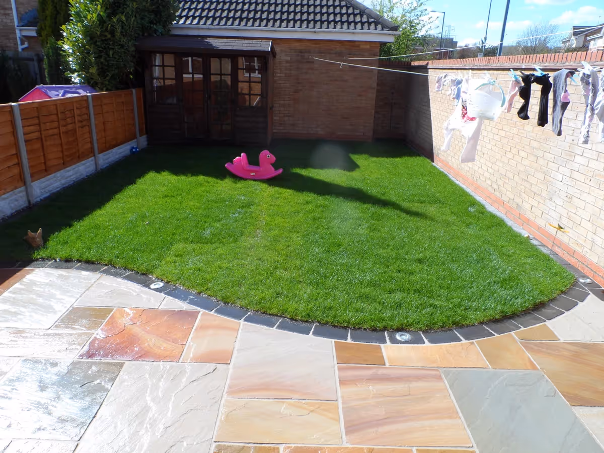 Mixed size camal natural stone patio with large charcoal rumbled block and step built from small key set kerbs - angle 5
