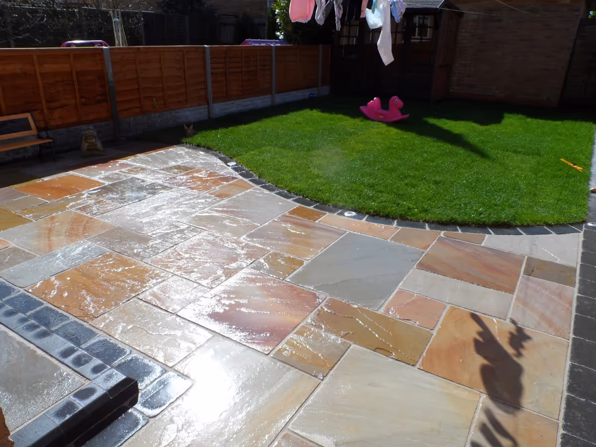 Mixed size camal natural stone patio with large charcoal rumbled block and step built from small key set kerbs - angle 2