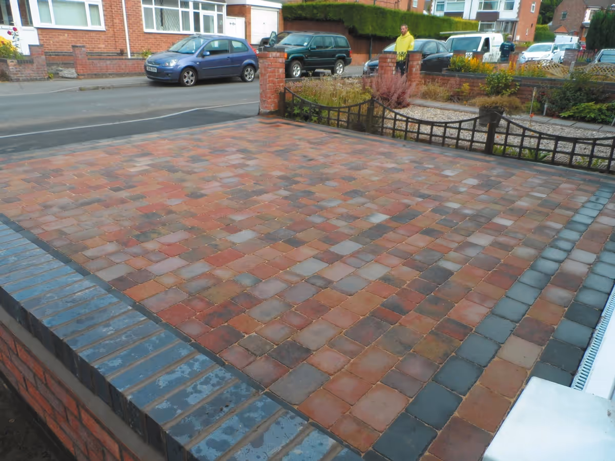 Orchid flame Rumbled paving set driveway with triple borders using charcoal, boundary wall installed and an ACO channel drainage system