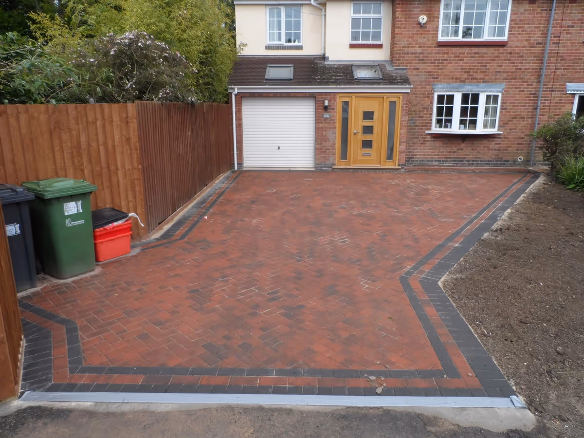 Brindle standard paving set driveway with triple borders using charcoal, Aco channel drainage system and a large planter area.
