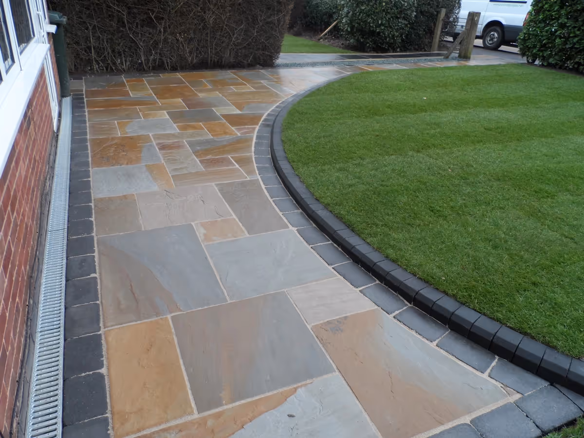 Camel Indian natural stone with rumbled charcoal borders, K.S kerb sets, ACO channel drainage system and new lawn using Rolawn medallion turf - angle 3