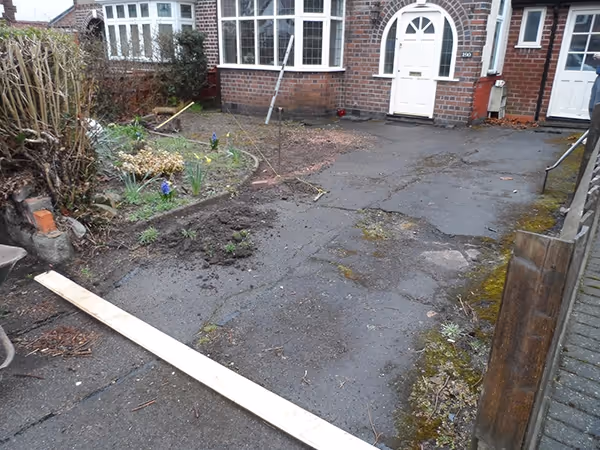 Bracken Rumbled paving set driveway with a single charcoal border, radius planter areas and an ACO channel drainage system.