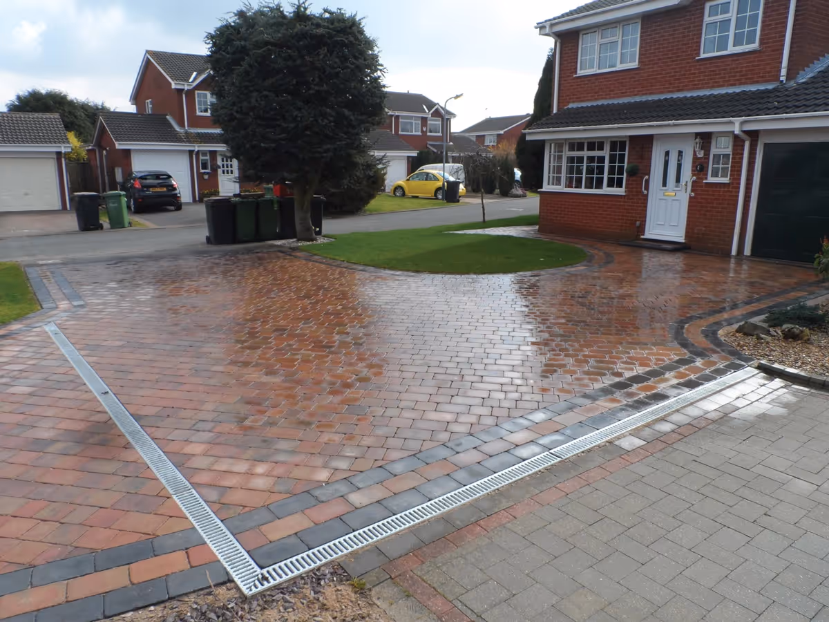 Autumn mix Rumbled paving set driveway with a triple border in charcoal, ACO channel drainage system and new lawn areas using Rolawn medallion turf - angle 2