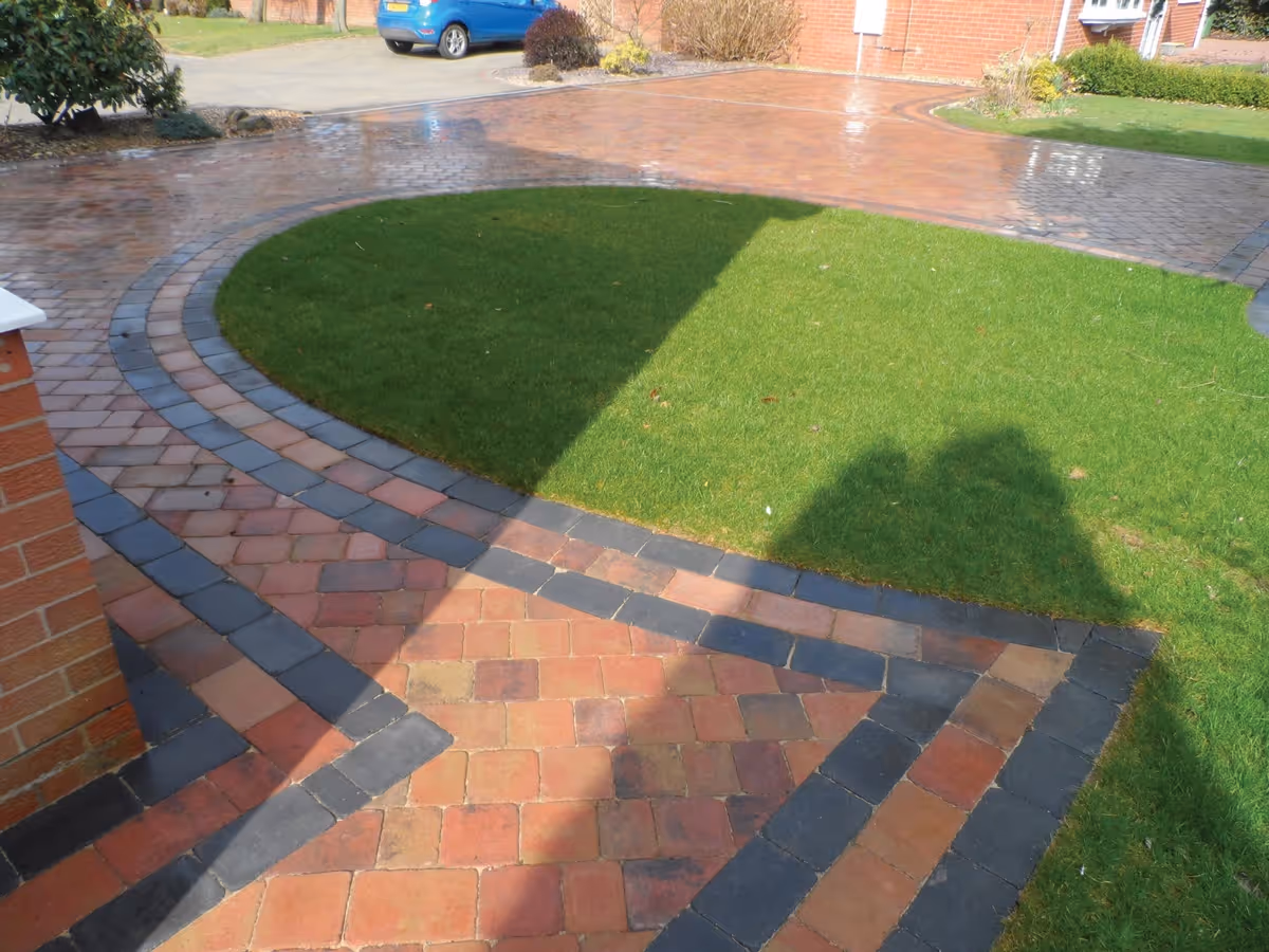 Autumn mix Rumbled paving set driveway with a triple border in charcoal, ACO channel drainage system and new lawn areas using Rolawn medallion turf - angle 4