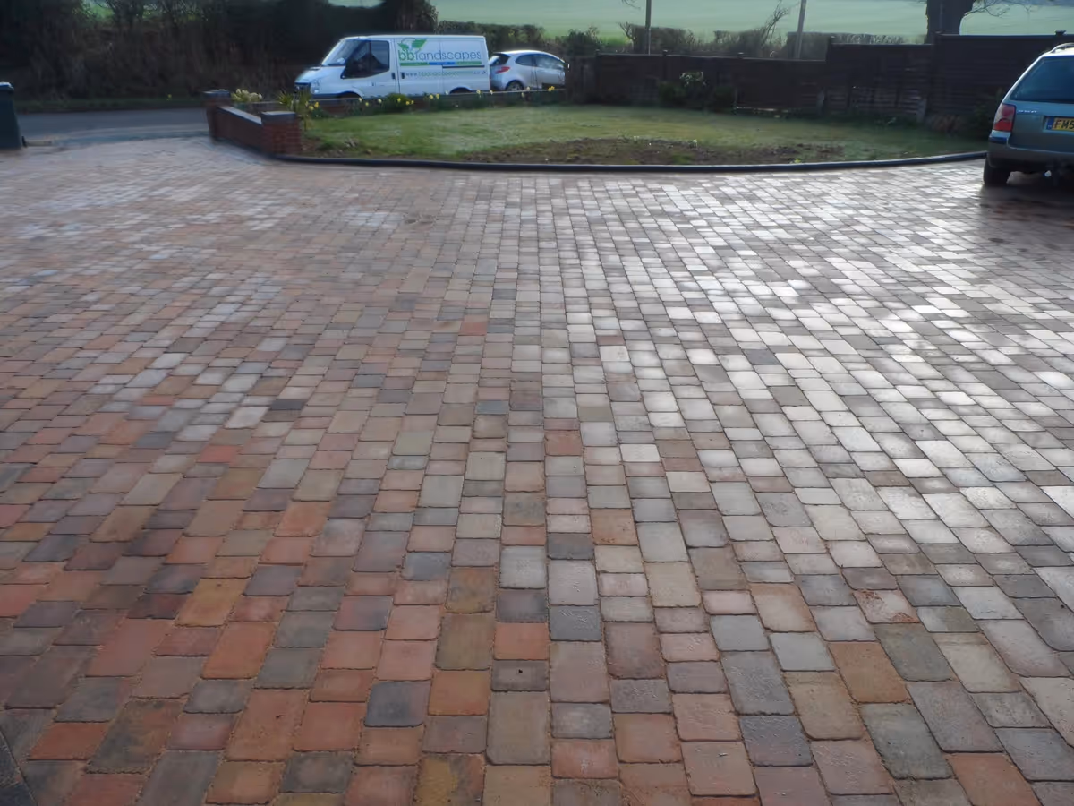 Orchid flame Rumbled paving set large driveway with a triple border using Charcoal, K.S kerb set lawn retainer, and an inset manhole tray- angle 2