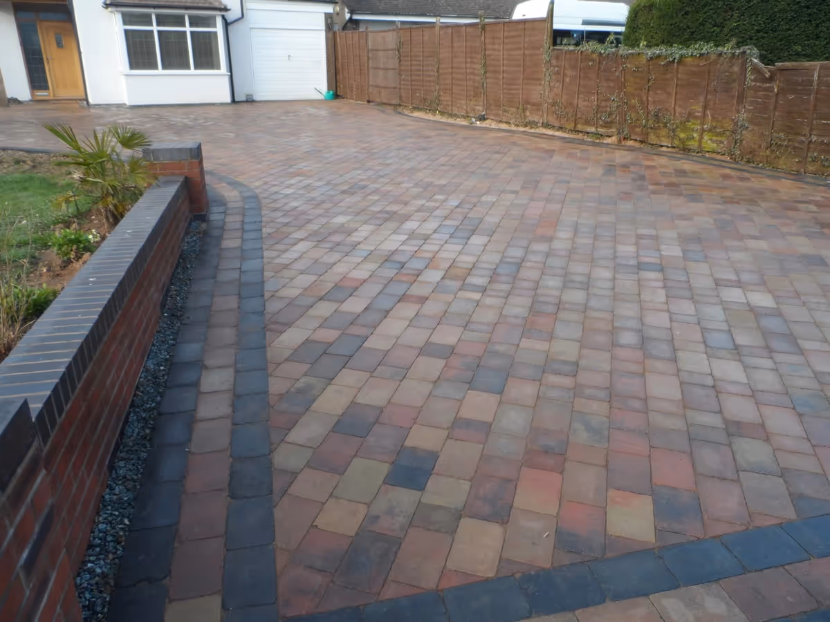 Orchid flame Rumbled paving set large driveway with a triple border using Charcoal, K.S kerb set lawn retainer, and an inset manhole tray- angle 4