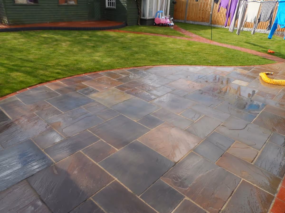 Mixed size camal natural stone patio with red standard blocks. Red standard block paving with standard charcoal block border - angle 3