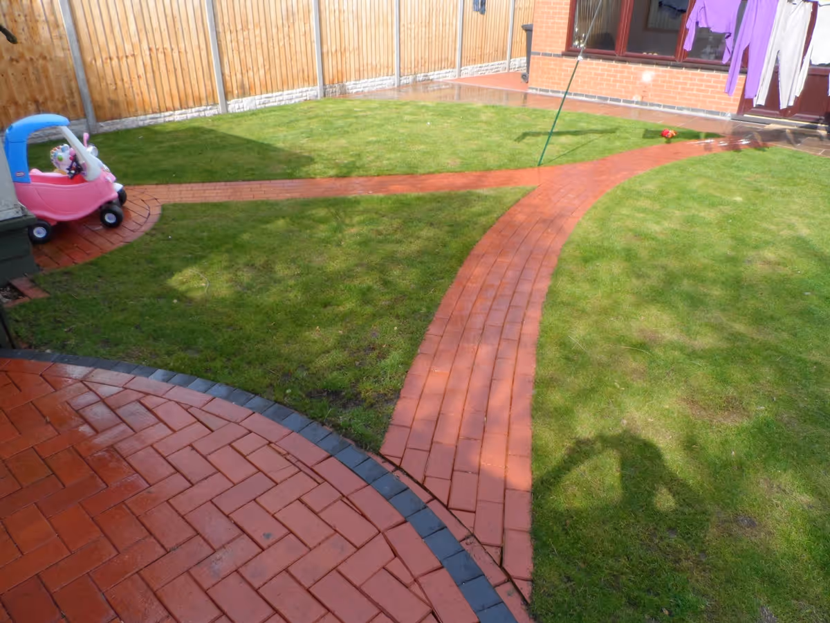 Mixed size camal natural stone patio with red standard blocks. Red standard block paving with standard charcoal block border - angle 2