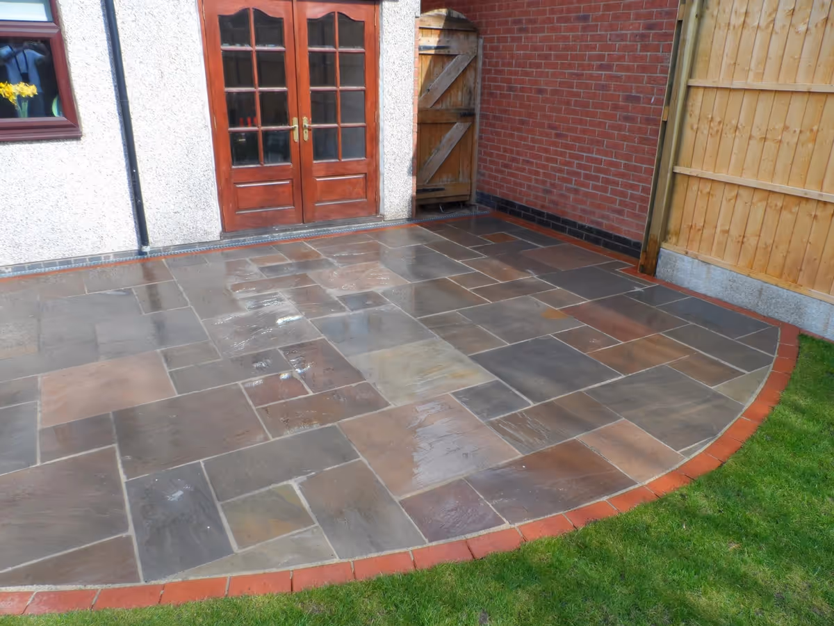 Mixed size camal natural stone patio with red standard blocks. Red standard block paving with standard charcoal block border - angle 4